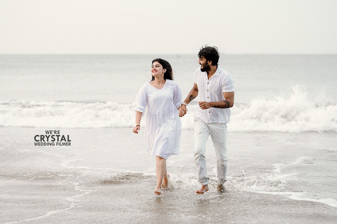 Couple walking along the Snehatheeram beach wearing white dress on their save the date photography in Kerala